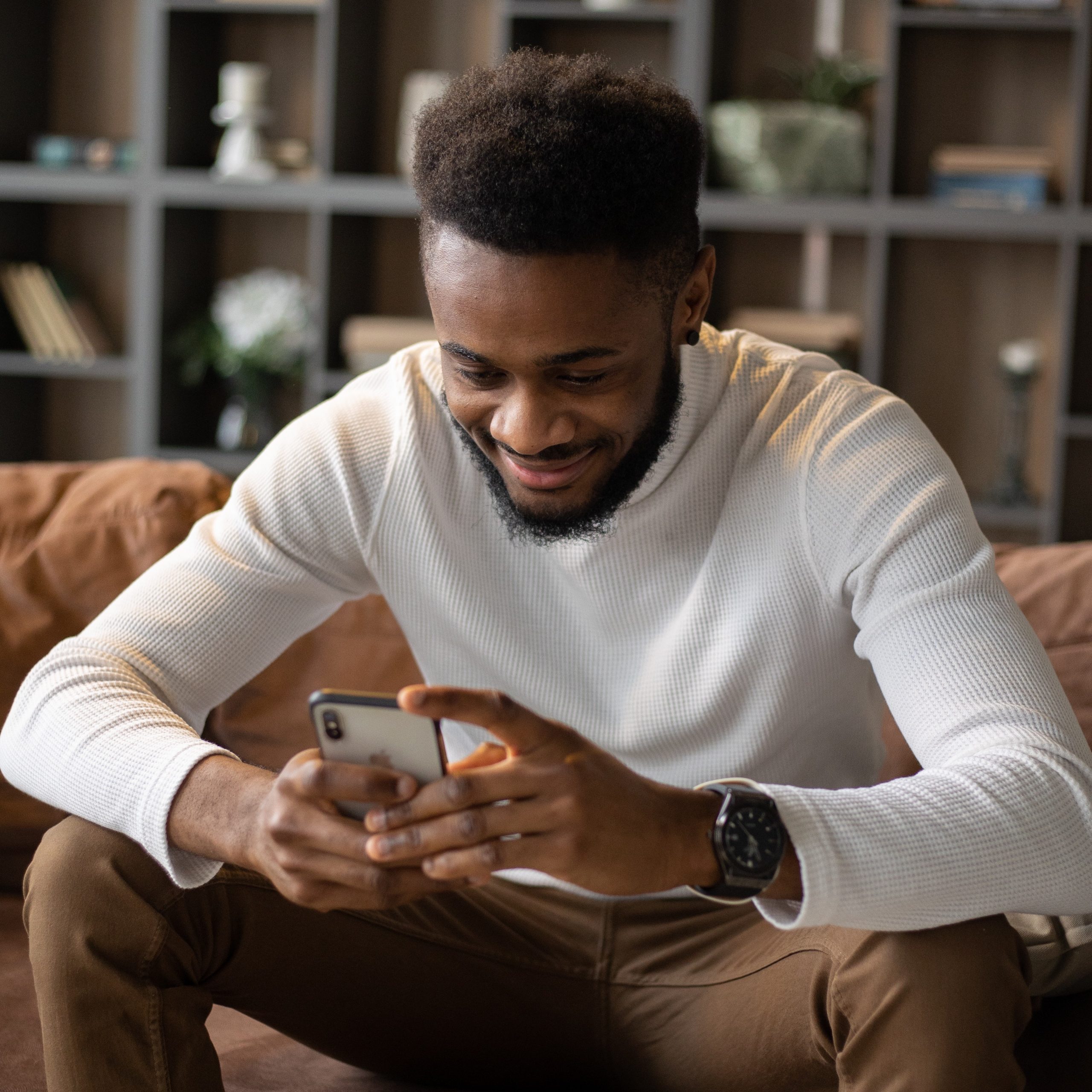 Man on the couch, texting in Spanish