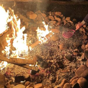 Cooking sausage on a grill over a campfire